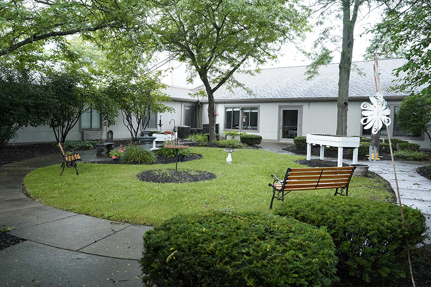 Park bench, trees and plants in outdoor courtyard- Arbors West